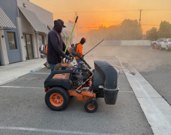 Crew using blower machines to thoroughly clean debris from an asphalt parking lot surface before sealcoating and striping