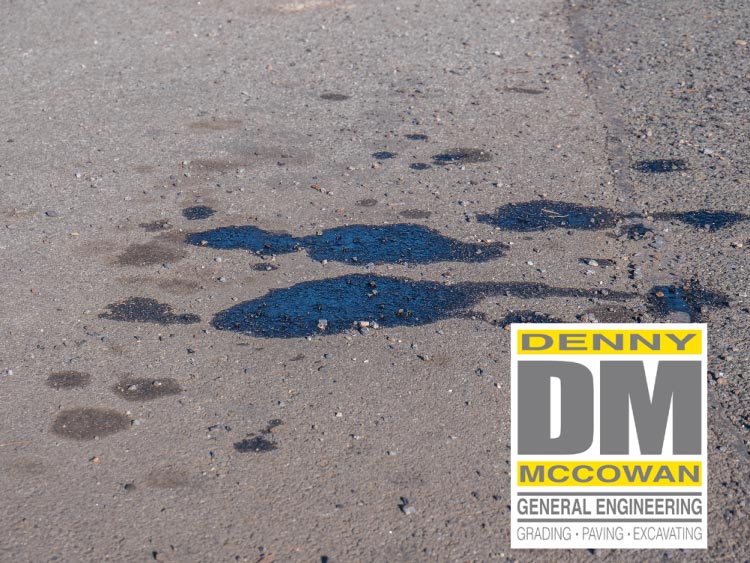 Close-up of dark oil stains damaging an asphalt surface, highlighting the critical need for professional asphalt maintenance, sealing, and repair services by Denny McCowan General Engineering.