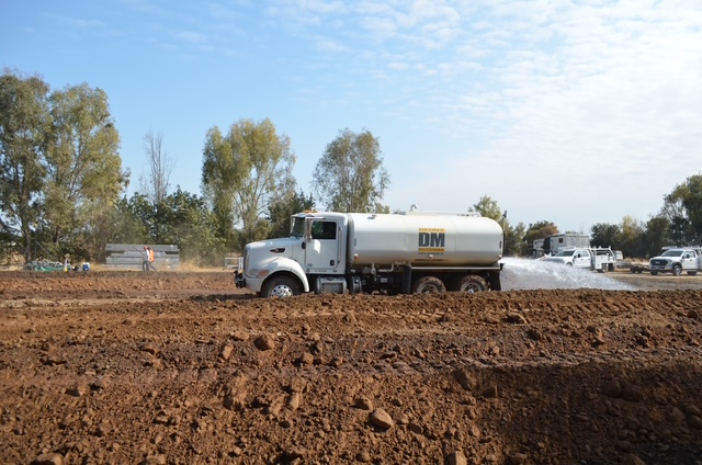 water truck applying dust control before compaction on a site preparation project in visalia, ca